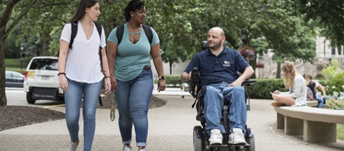diverse students traveling together, two walking and one using motorized wheelchair