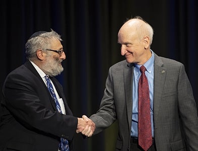 David Brent and Jeff Inman shake hands on stage at 2022 Faculty Honors Convocation