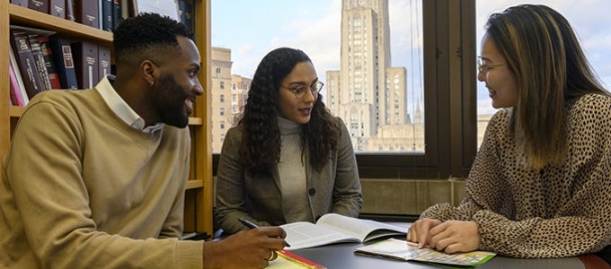 three Pitt Law students gathered around table with study materials