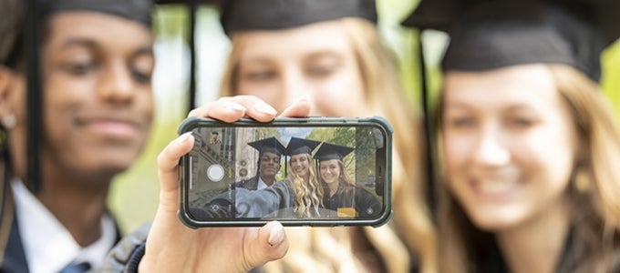 Graduates showing selfie in caps and gowns