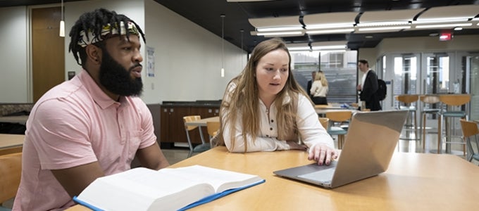 Pitt Law students working together on laptop with textbook