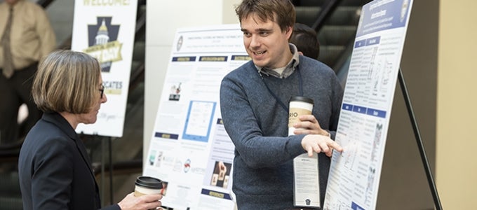 Postdoctoral fellow Lawrence Andrews explains his work on Immunology to Provost Ann Cudd at Pitt Day in Harrisburg