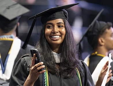 smiling female undergrad student in cap and gown at commencement