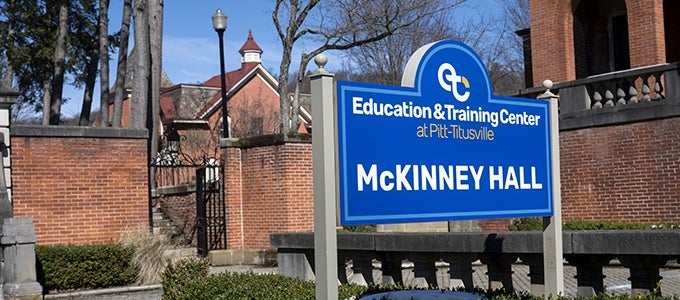 Large blue sign reading "McKinney Hall" outside its building at the Education and Training Center at Pitt-Titusville.