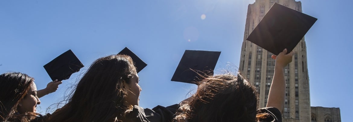 graduates throwing caps in the air in front of Cathedral of Learning