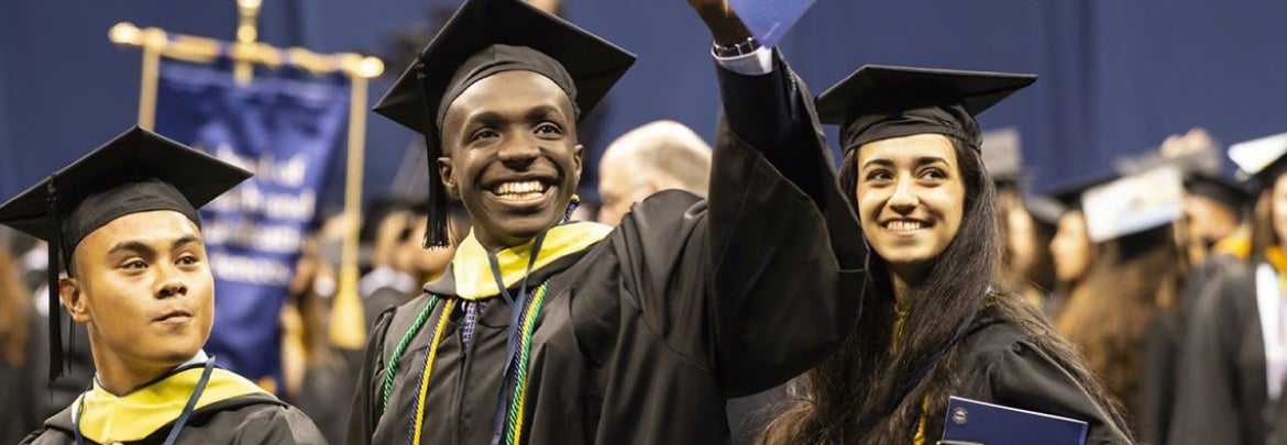 smiling Pitt graduates in caps and gowns