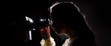 A person looking through a microscope A person looking through a microscope