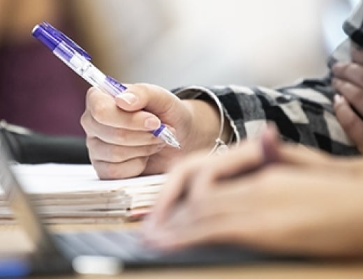 closeup of Pitt students taking notes in class