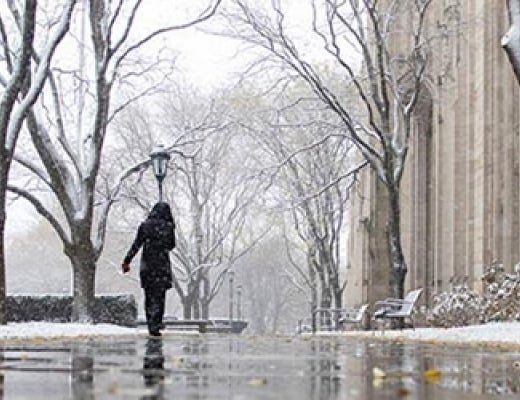 Pitt student walking on snowy campus sidewalks